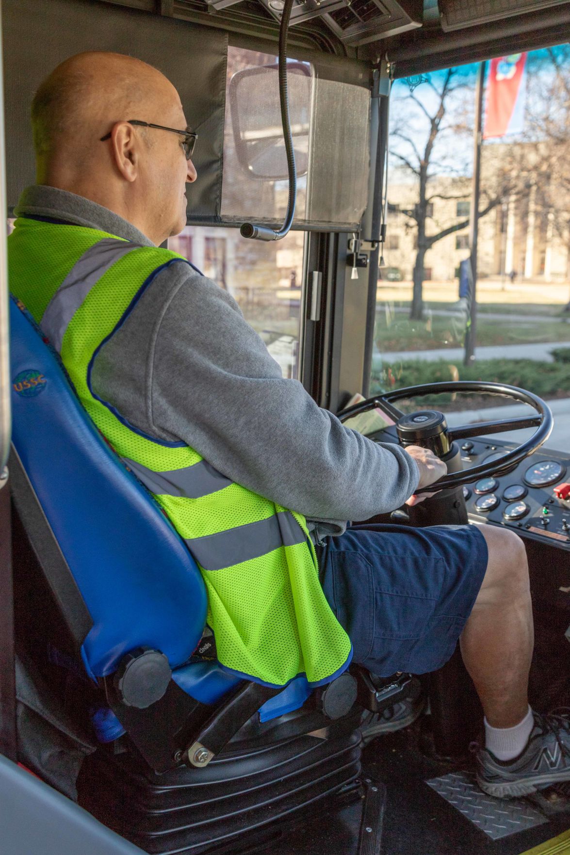 K.U. bus driver Rex Gardner sits in the driver's seat of his bus and looks at the road